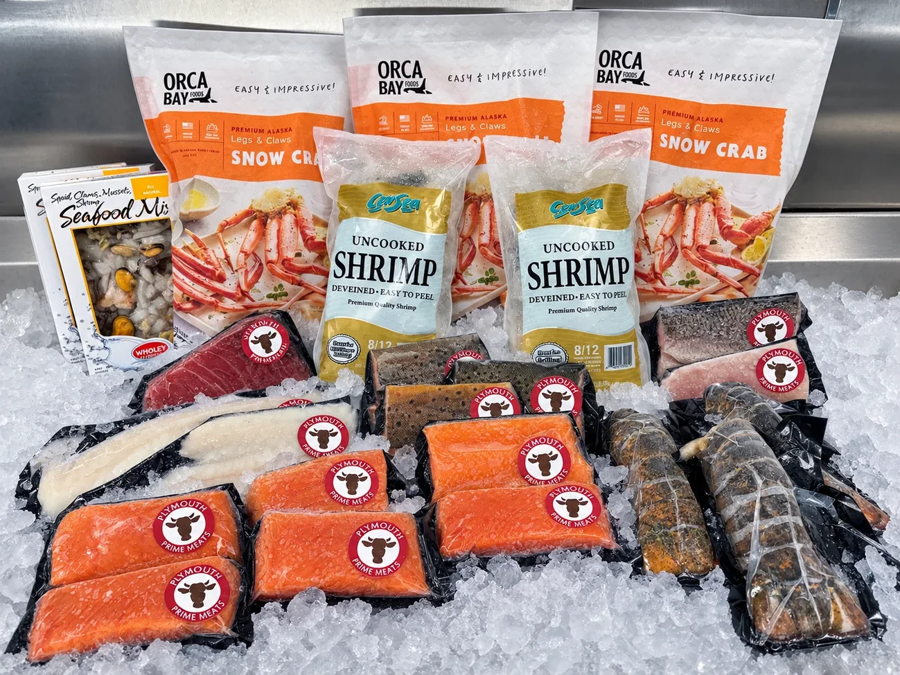 Fresh salmon, shrimp, snow crab and lobster tails displayed on ice